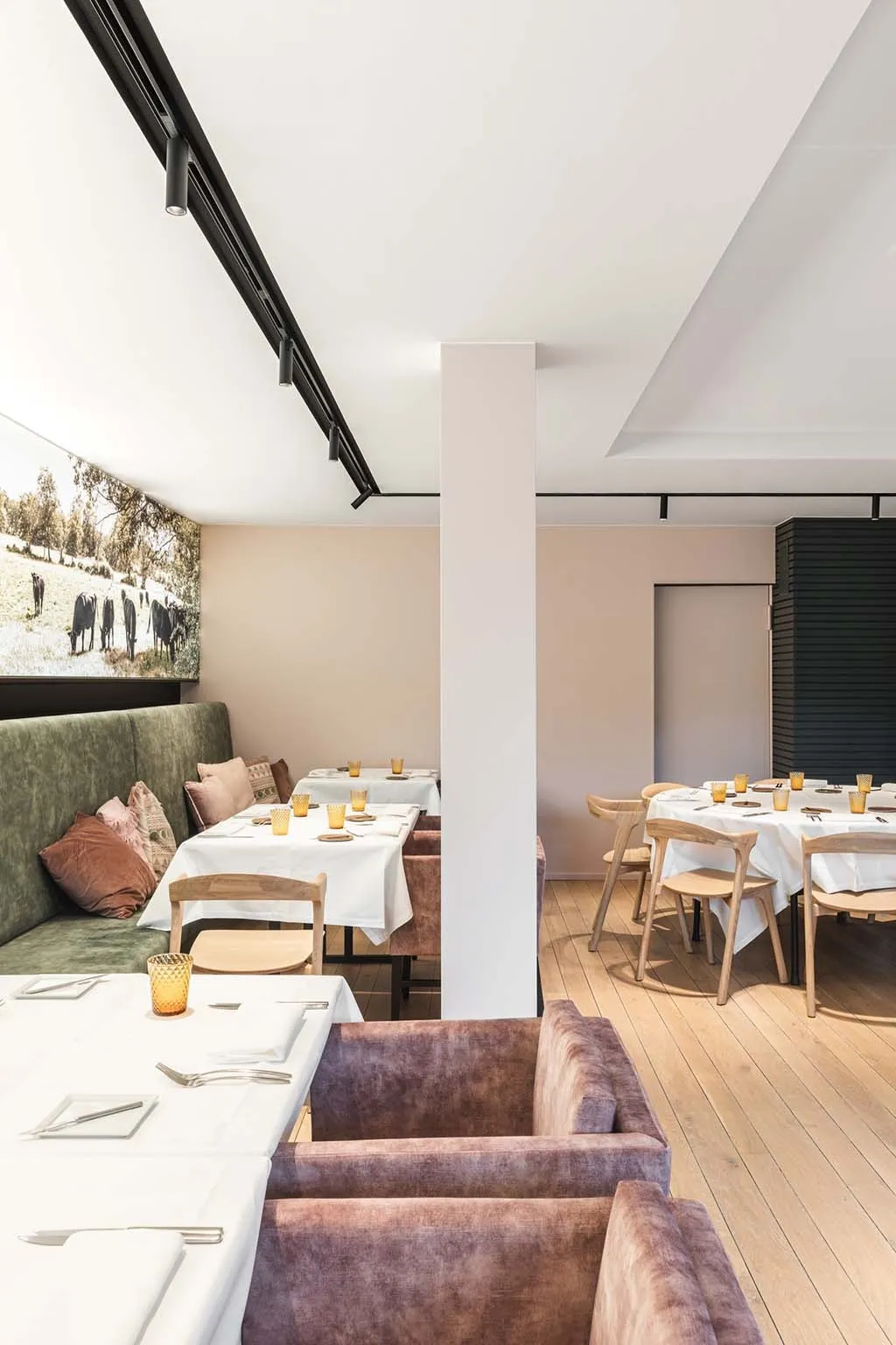 De zaal rond de witte pilaar: mauve fluwelen stoelen op de voorgrond en gedekte tafels erachter
